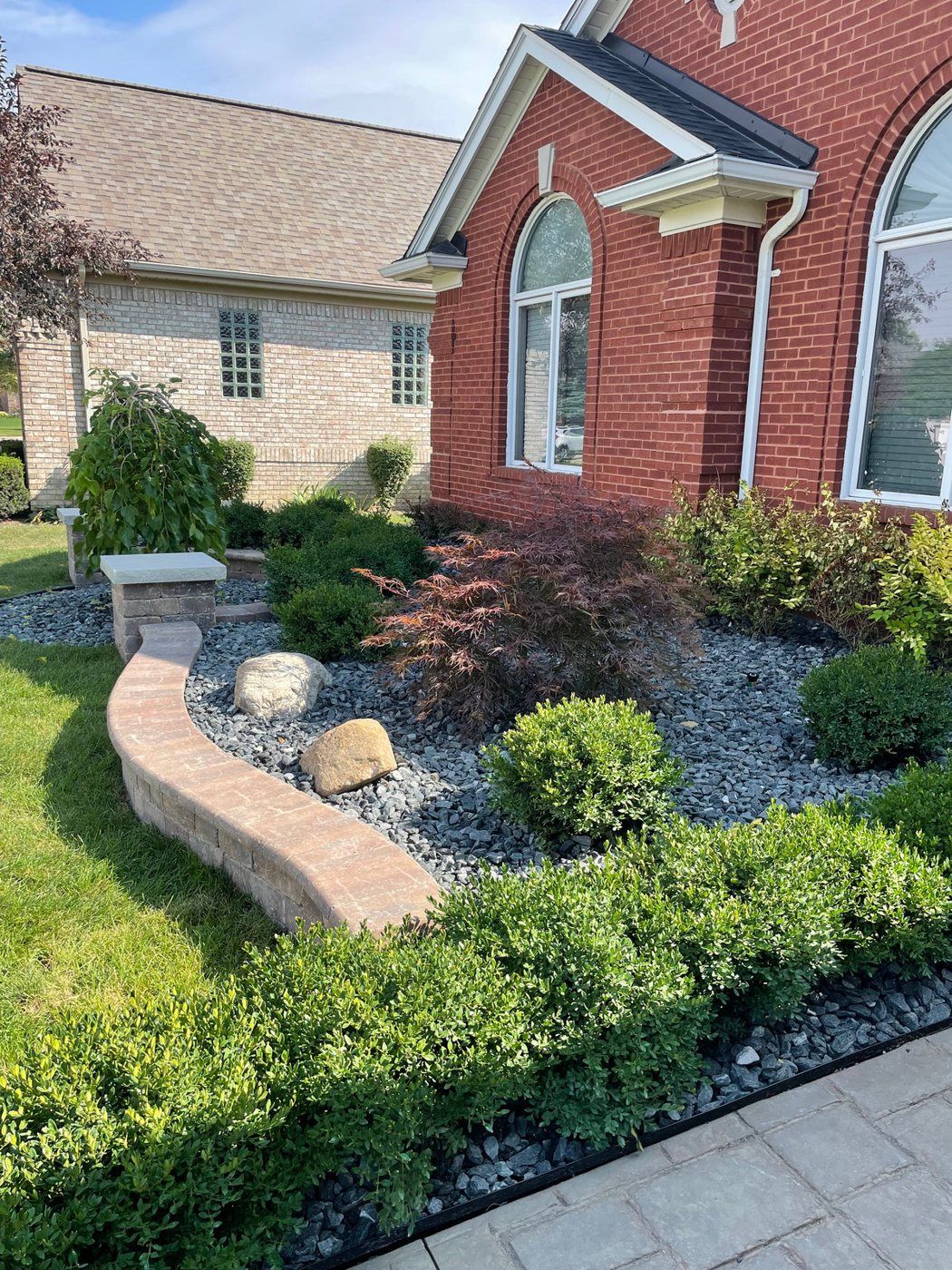 New landscape beds with shrubs and stone along a brick home