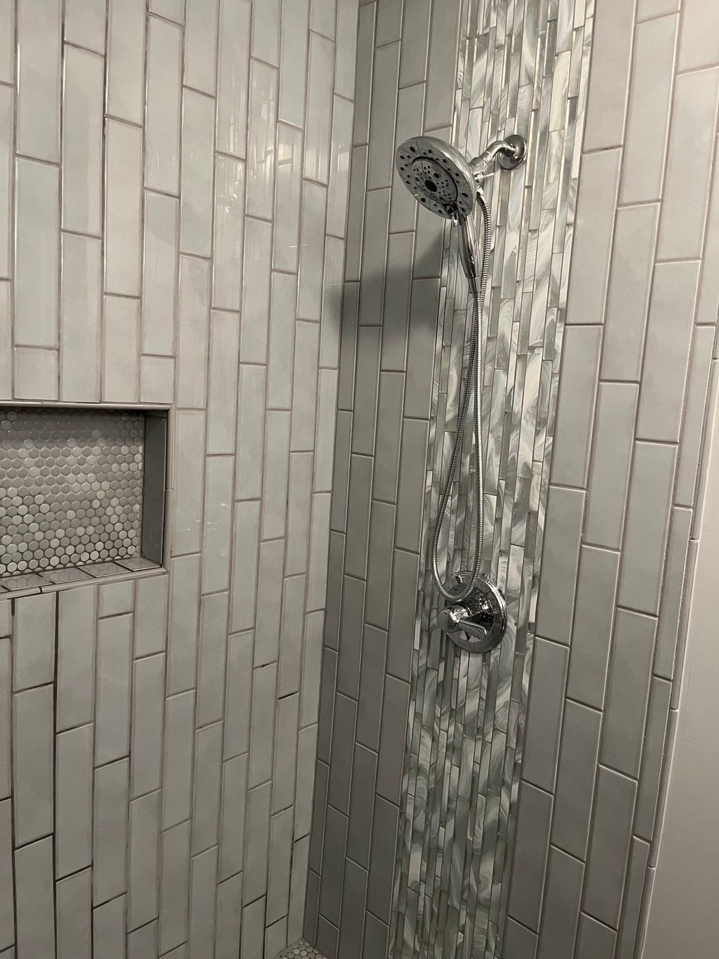 Tiled shower with a mosaic accent stripe and niche